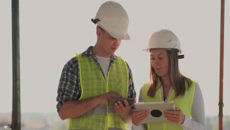 Supervisor-De-Un-Edificio-En-Construcción,-Un-Hombre-Discutiendo-Con-Una-Ingeniera-Diseñadora-Sobre-El-Progreso-De-La-Construcción-Y-Examina-Un-Plan-De-Construcción.